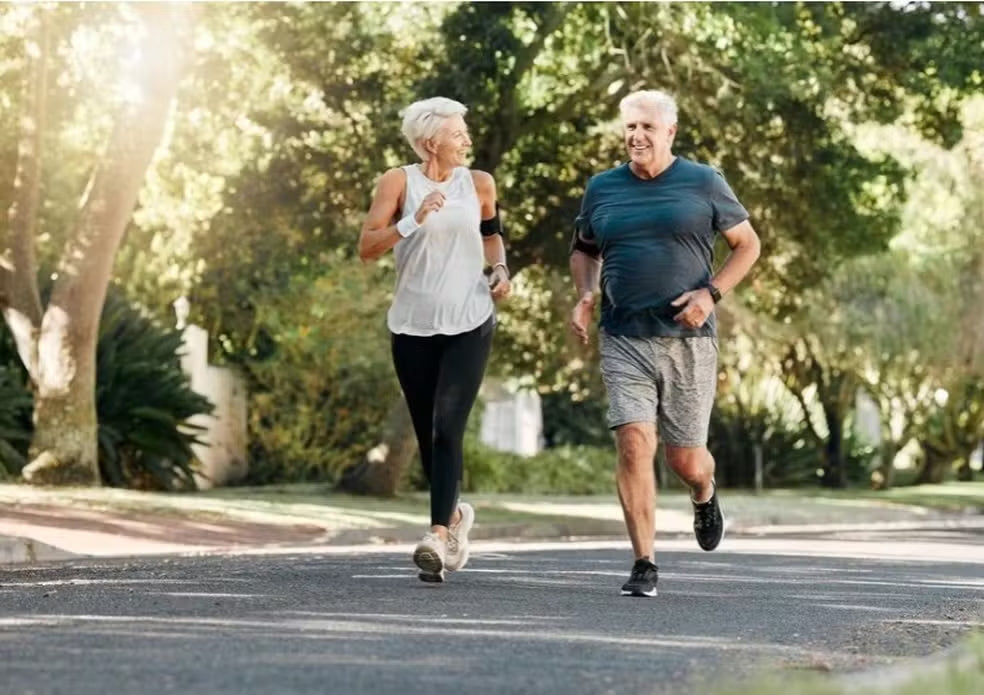 Duas pessoas a correr num percurso arborizado